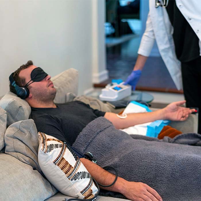 A man on a couch being treated with sedative IV therapy