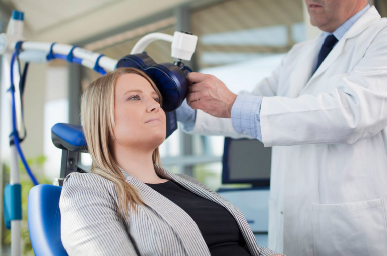A woman receiving rTMS, with a doctor positioning a machine near her head.